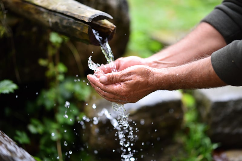 How to Stay Clean When Hiking — Man Washing his Hands with Mountain Spring Water.